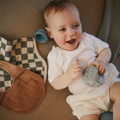 Bébé souriant avec jouet sensoriel et bavoirs en coton pour maternité et soins bébé