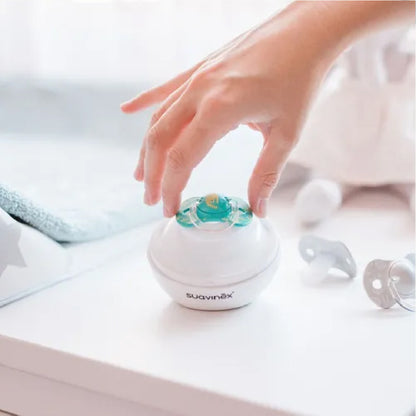 Main déposant une tétine dans un stérilisateur pour bébé, accessoire maternité pratique et hygiénique